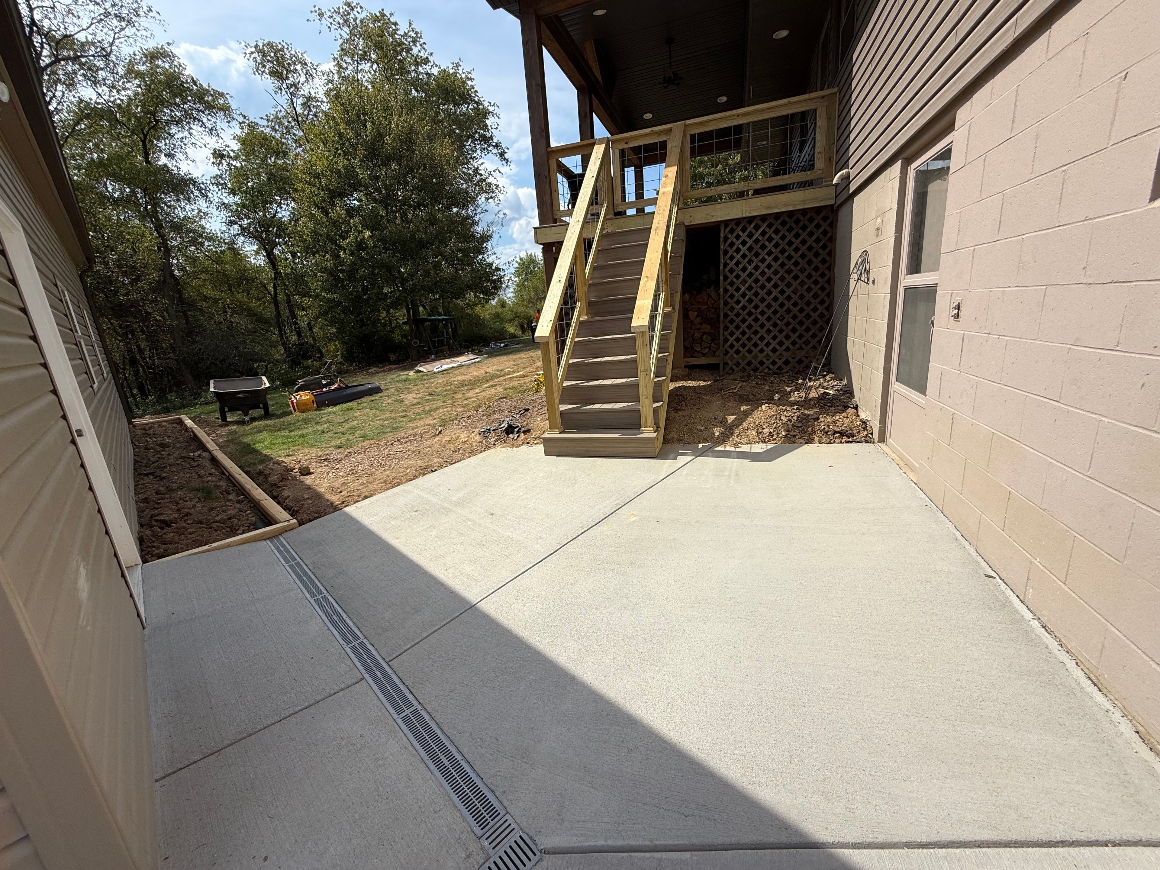 New concrete patio with deck stairs and backyard